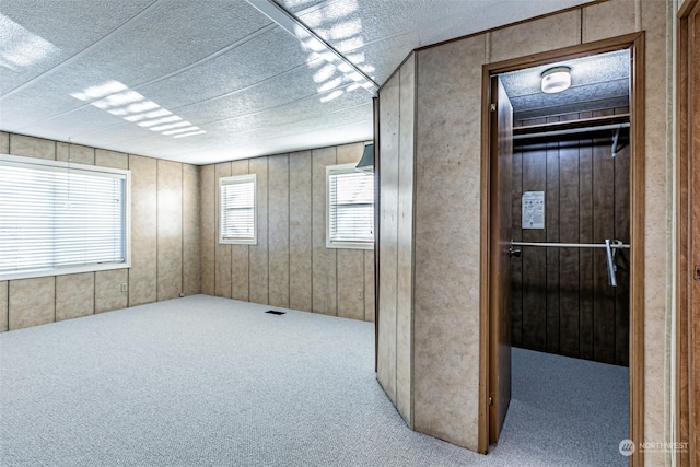 unfurnished room with light colored carpet and wooden walls