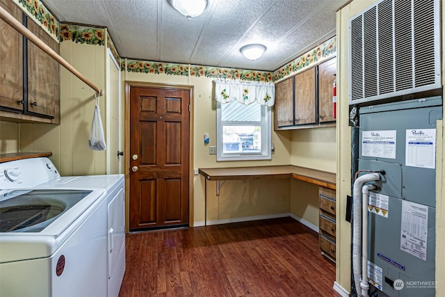 clothes washing area with cabinets, washing machine and clothes dryer, dark wood-type flooring, a textured ceiling, and heating unit