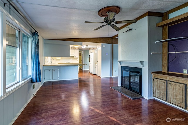 unfurnished living room featuring ceiling fan, sink, dark hardwood / wood-style floors, and vaulted ceiling