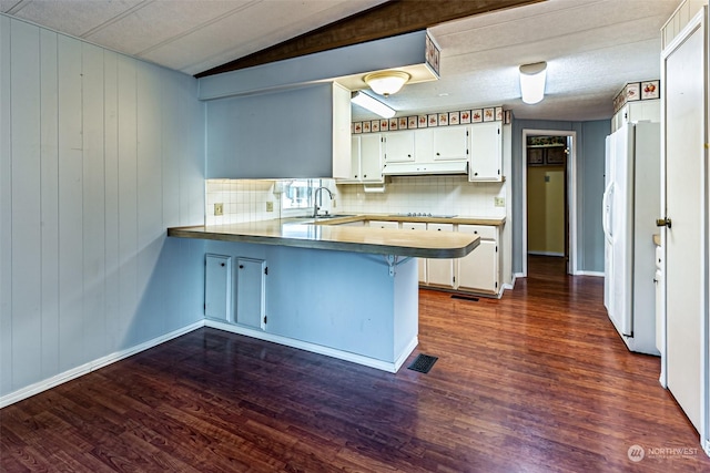 kitchen with dark wood-type flooring, sink, kitchen peninsula, white fridge with ice dispenser, and white cabinetry