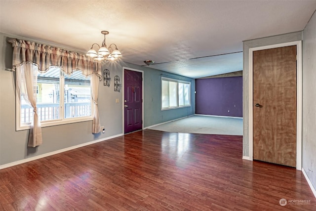 empty room featuring a textured ceiling, dark hardwood / wood-style floors, an inviting chandelier, and plenty of natural light