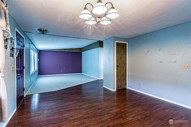 unfurnished room with a textured ceiling, dark hardwood / wood-style floors, and an inviting chandelier