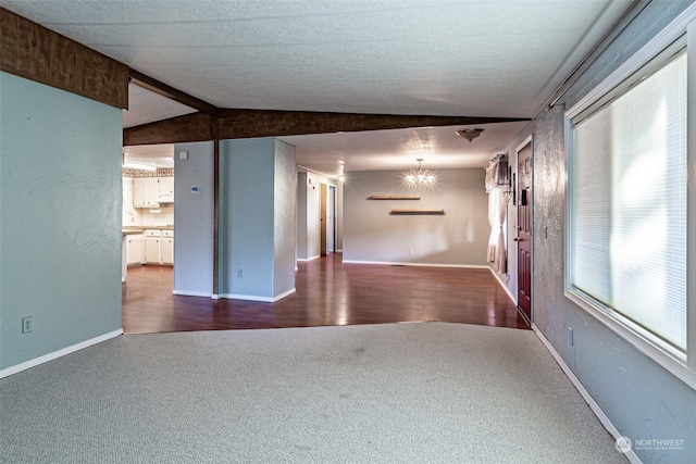 unfurnished room with carpet floors, lofted ceiling, and an inviting chandelier