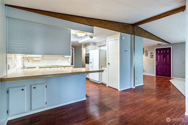 kitchen with kitchen peninsula, tasteful backsplash, sink, white refrigerator with ice dispenser, and lofted ceiling with beams