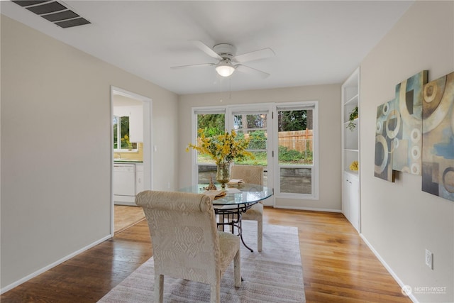 dining space featuring built in shelves, ceiling fan, and light hardwood / wood-style flooring