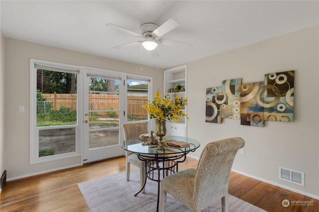 dining room with light hardwood / wood-style floors, built in features, and ceiling fan