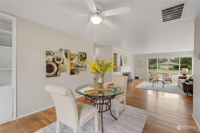 dining space with light wood-type flooring, built in features, and ceiling fan