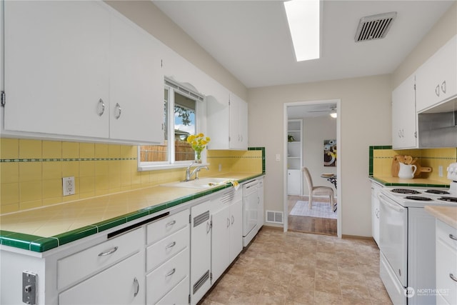 kitchen with backsplash, white cabinetry, tile counters, and white appliances