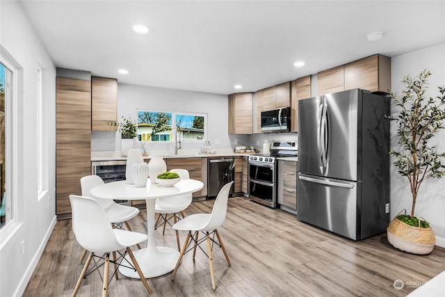 kitchen featuring light brown cabinets, light hardwood / wood-style floors, and appliances with stainless steel finishes