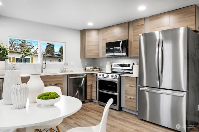 kitchen with appliances with stainless steel finishes, light hardwood / wood-style flooring, and sink