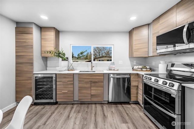 kitchen featuring sink, stainless steel appliances, wine cooler, and light hardwood / wood-style flooring