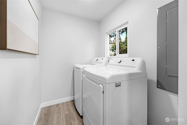 laundry area with independent washer and dryer, electric panel, and light hardwood / wood-style flooring