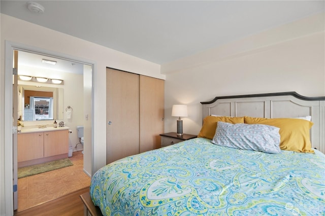 bedroom featuring ensuite bathroom, a closet, sink, and light hardwood / wood-style flooring