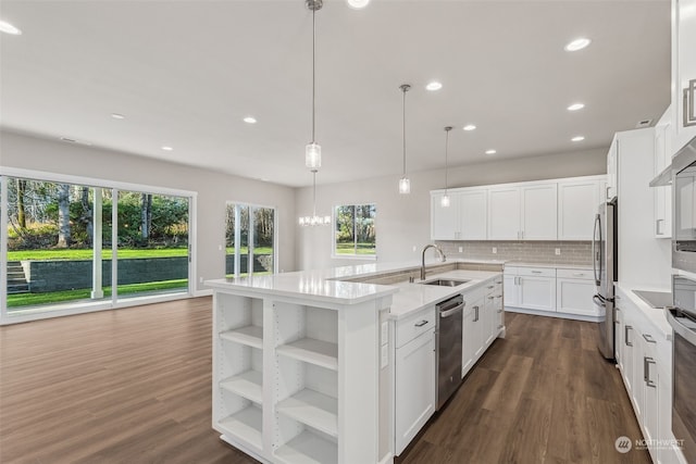 kitchen with a kitchen island with sink, sink, appliances with stainless steel finishes, decorative light fixtures, and white cabinetry