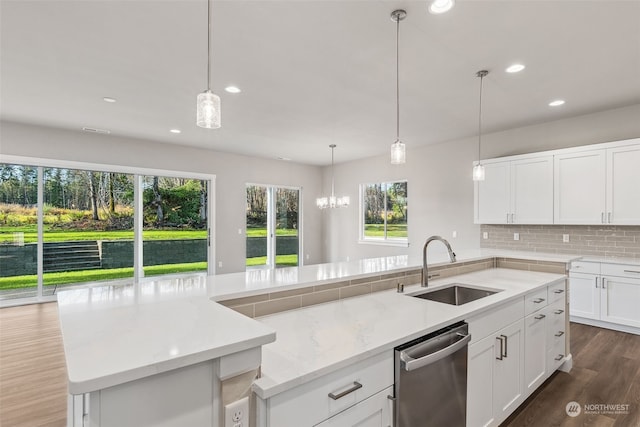 kitchen with light stone countertops, sink, stainless steel dishwasher, a center island with sink, and white cabinets