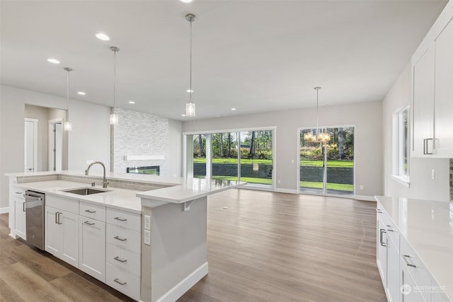 kitchen with dishwasher, sink, an island with sink, pendant lighting, and white cabinets