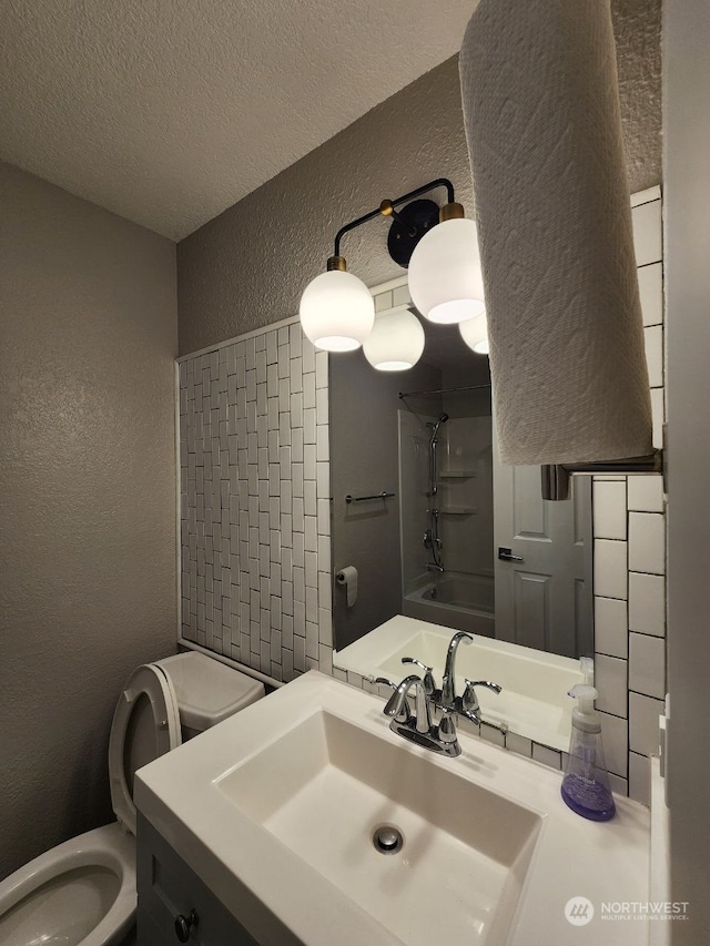 full bathroom featuring vanity, a textured ceiling, toilet, and shower / washtub combination