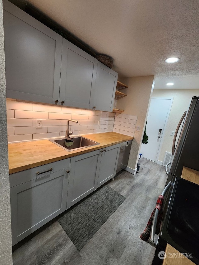 kitchen with wood counters, a textured ceiling, sink, gray cabinets, and light hardwood / wood-style floors