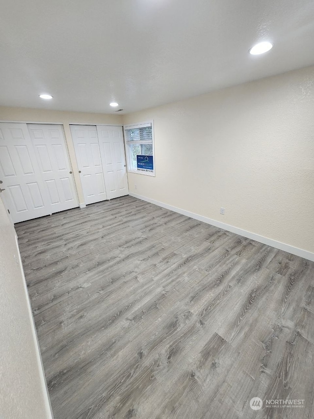 unfurnished bedroom with light hardwood / wood-style floors and multiple closets