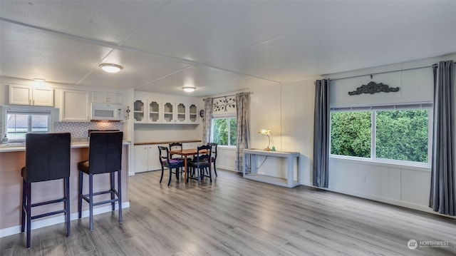 kitchen featuring a kitchen bar, light wood-type flooring, and white cabinetry