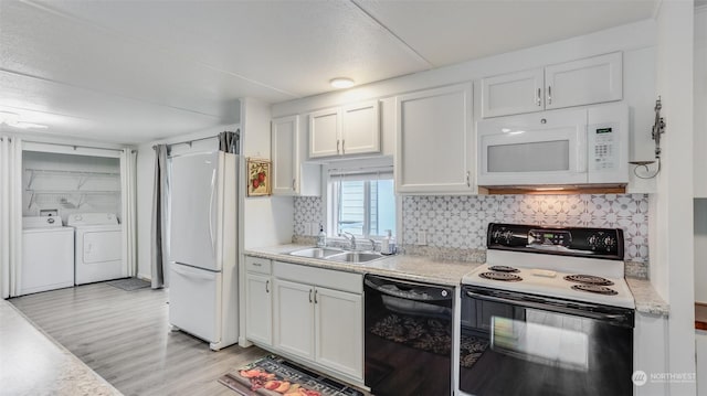 kitchen featuring washing machine and clothes dryer, white appliances, white cabinetry, and sink