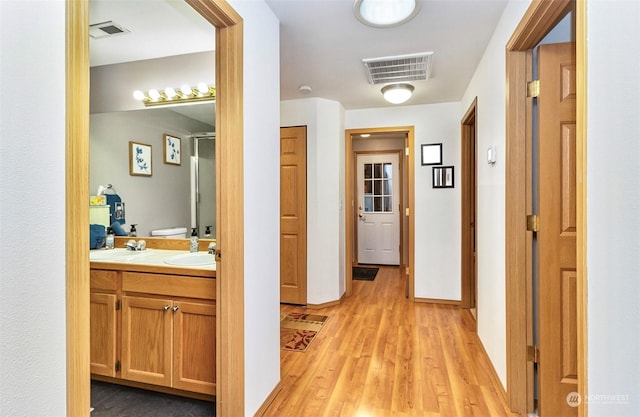 corridor featuring sink and light hardwood / wood-style flooring