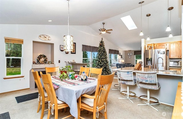 dining room featuring ceiling fan, light colored carpet, lofted ceiling with skylight, and sink