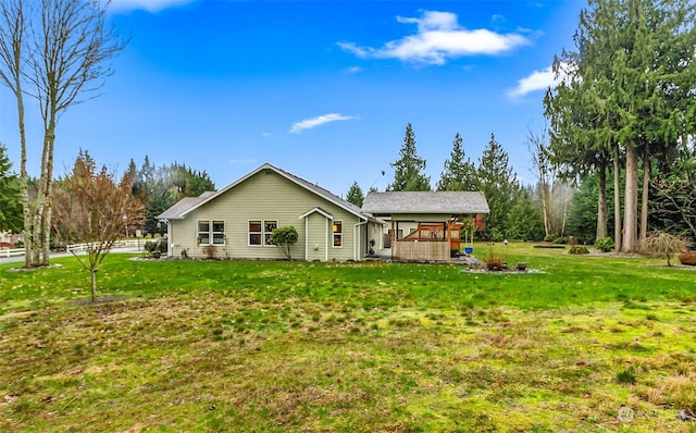 rear view of property featuring a yard and a wooden deck