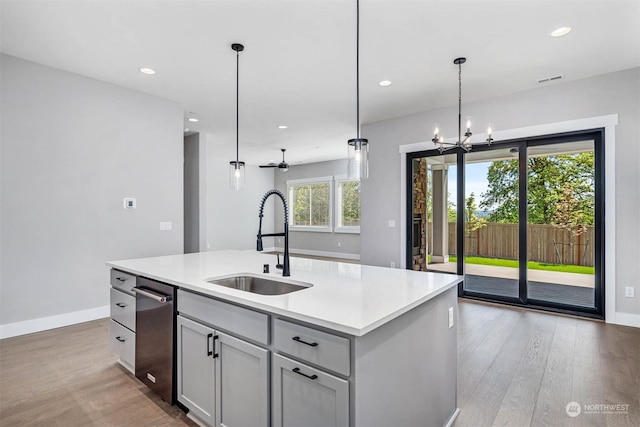 kitchen featuring ceiling fan with notable chandelier, sink, hanging light fixtures, an island with sink, and a wealth of natural light