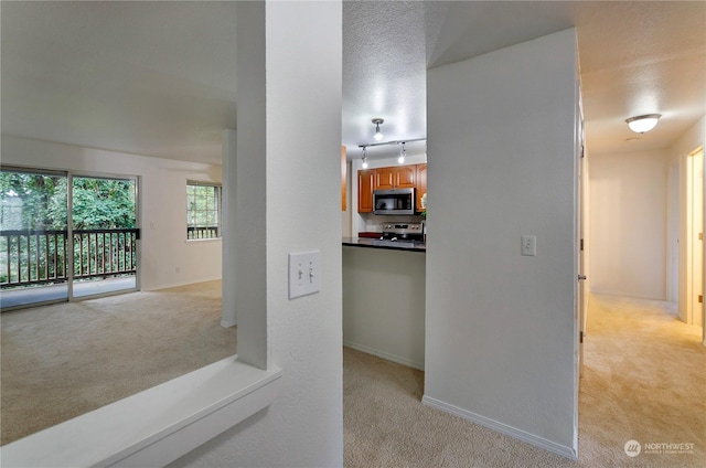 corridor featuring a textured ceiling and light carpet