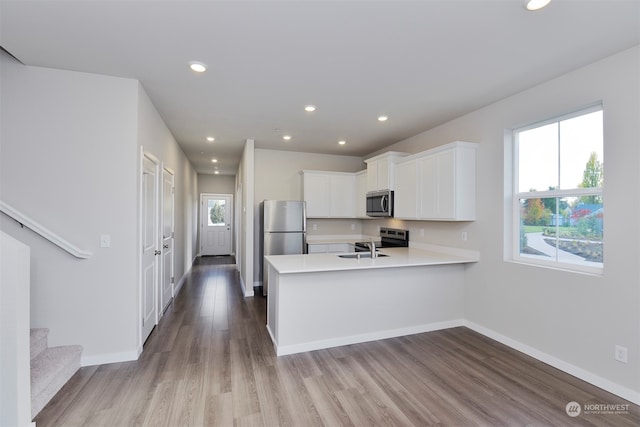 kitchen featuring kitchen peninsula, plenty of natural light, white cabinetry, and stainless steel appliances