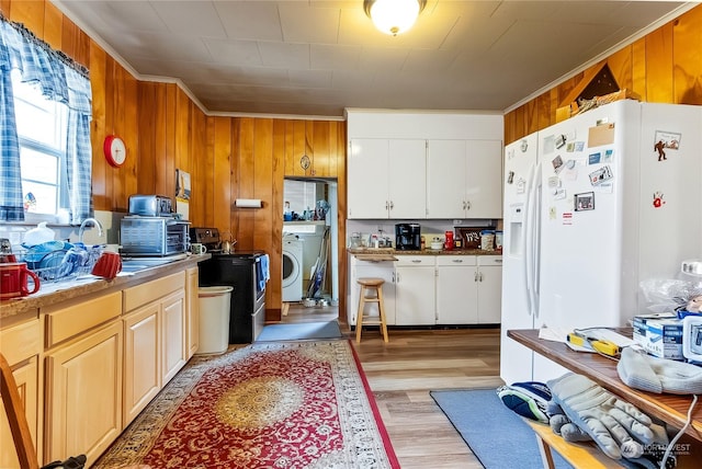 kitchen featuring washer / clothes dryer, white cabinetry, wooden walls, and white refrigerator with ice dispenser