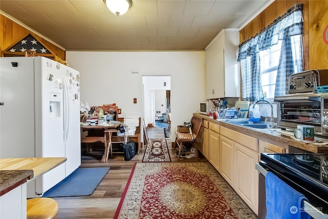 kitchen with white refrigerator with ice dispenser, electric stove, sink, ornamental molding, and wood-type flooring