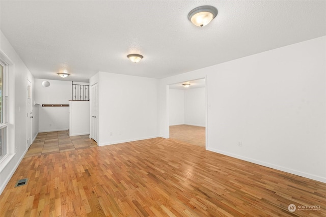 empty room with a textured ceiling and light wood-type flooring