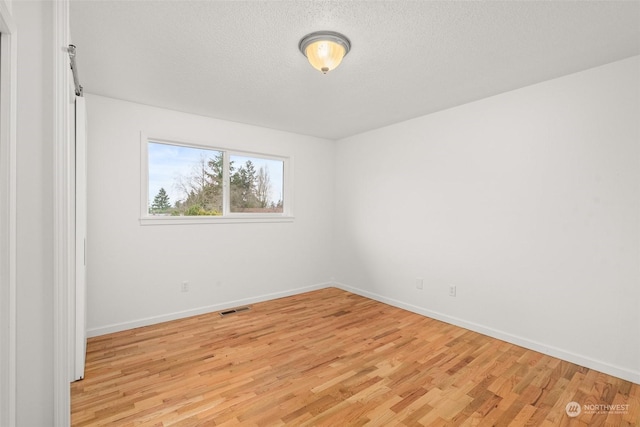 unfurnished room with a textured ceiling and light hardwood / wood-style floors