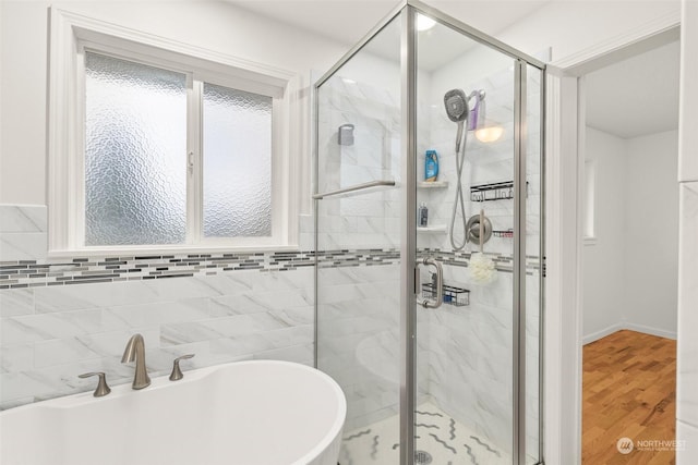 bathroom featuring hardwood / wood-style floors, tile walls, and independent shower and bath