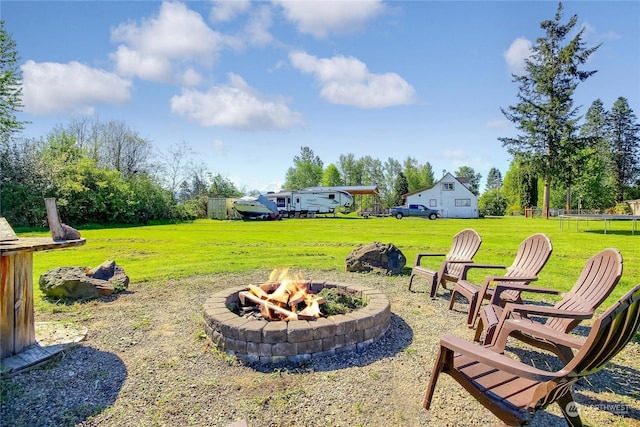 view of yard featuring a fire pit and a trampoline