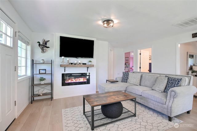 living room featuring light wood-type flooring and a large fireplace