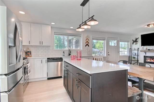 kitchen featuring white cabinets, appliances with stainless steel finishes, decorative backsplash, and pendant lighting