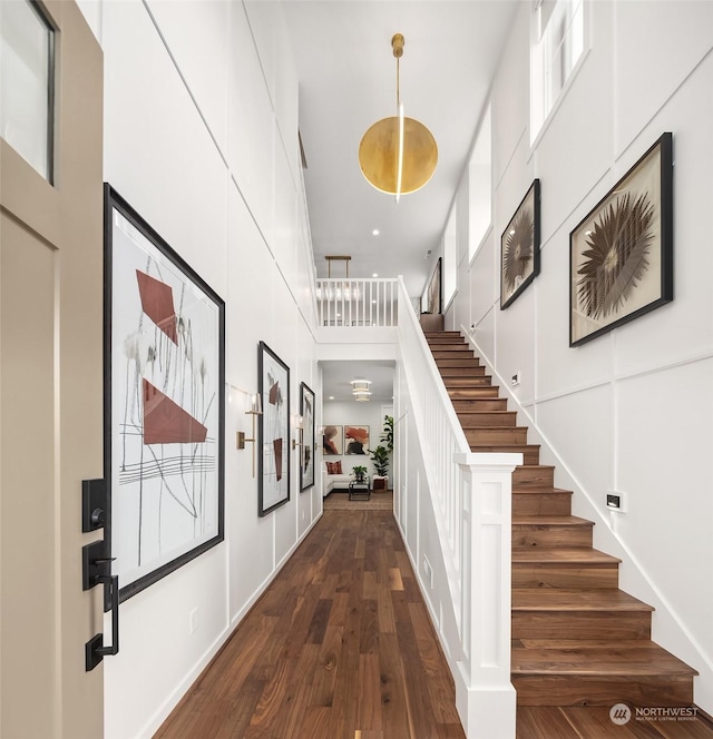 foyer entrance featuring stairs, a high ceiling, and dark wood-style flooring