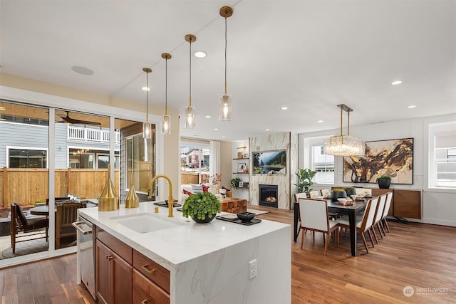 kitchen featuring recessed lighting, a large fireplace, wood finished floors, a sink, and pendant lighting