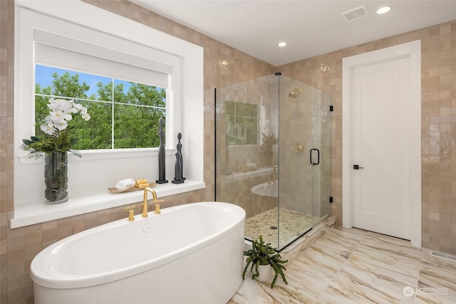 full bath with a stall shower, visible vents, marble finish floor, a freestanding tub, and tile walls