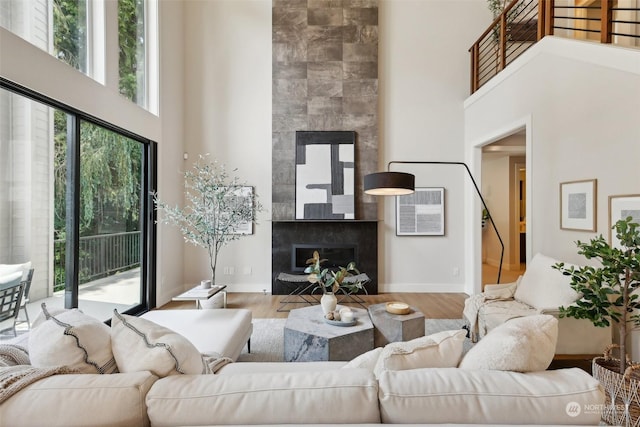 living room with a large fireplace, a towering ceiling, and light hardwood / wood-style floors