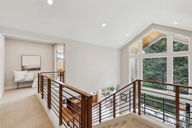 corridor featuring a healthy amount of sunlight, light colored carpet, and lofted ceiling