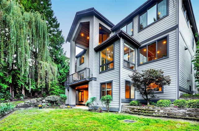 view of front of home with a balcony and a front lawn