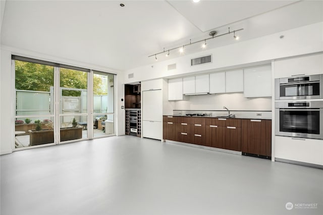 kitchen with sink, white cabinetry, dark brown cabinets, white fridge, and stainless steel double oven