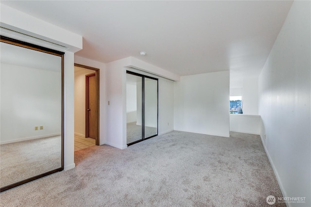 unfurnished bedroom featuring light carpet and a closet