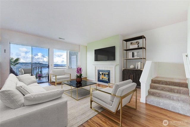 living room with a tiled fireplace and wood-type flooring