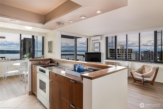 2100 3rd Ave Unit 2503, Seattle, WA 98121 - kitchen with a wall unit AC, white electric range oven, modern cabinets, plenty of natural light, and recessed lighting