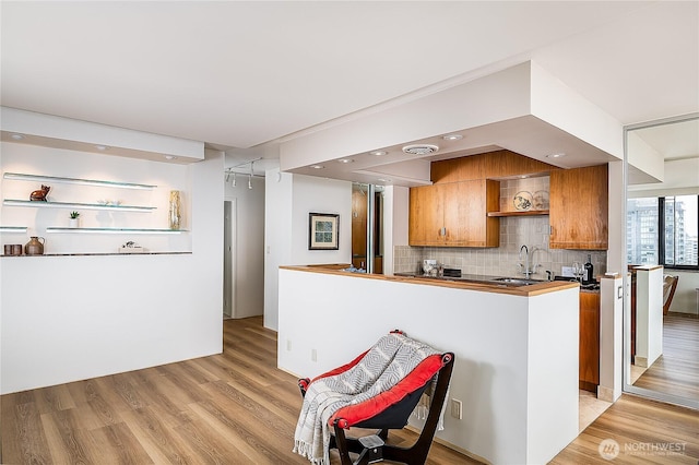 2100 3rd Ave Unit 2503, Seattle, WA 98121 - kitchen featuring brown cabinetry, decorative backsplash, light wood-type flooring, and open shelves